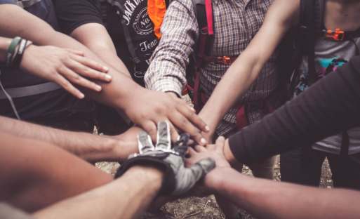 People cheering and holding hands in circle; photo by Dio Hasbi Saniskoro