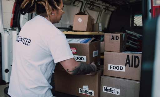 A volunteer sorting through boxes of food and medicine